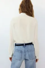 Blusa de mezcla de algodón y viscosa, color blanco con diseño a rayas finas oscuras, cuello alto con volados y mangas largas con puños elastizados con volados.