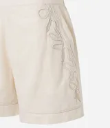Short de cintura alta color crema, con bolsillos laterales y bordados abstractos en los costados.