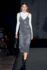 Polera blanca de tejido de punto fino, con cuello alto y manga larga. Tiene un pequeño logo de estrella bordado en el pecho.