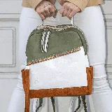 Mochila de cuero vacuno color verde oliva, blanco y marrón. Tiene un bolsillo frontal con cierre, dos bolsillos laterales, interior forrado con bolsillo con cierre y bolsillo para celular. Las correas son removibles.