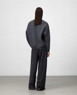 Jersey de lana gris melange, con cuello en V y manga larga. Presenta remates en canalé en puños y bajo.