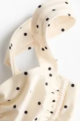 Top de bikini balconette de color beige con estampado de lunares negros. Cuenta con copas con aros y tirantes anchos.