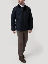 Chaqueta de hombre color azul marino, confeccionada en tela encerada impermeable y cortaviento. Cuenta con cuello de cotelé, cierre frontal con broches y cremallera, y múltiples bolsillos exteriores e interiores. El interior está forrado en franela y tiene relleno de THERMORE, hecho de fibras recicladas.