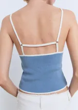Top de punto fino sin mangas, con diseño entallado, tirantes finos y cuello escotado. Presenta un detalle de borde en contraste en el escote y el ruedo.
