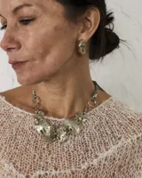 Gargantilla de diseño artesanal compuesta por eslabones metálicos con textura orgánica y acabado irregular. El diseño se ajusta al cuello mediante un cordón regulable.