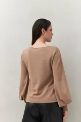 Top negro de tejido sutilmente metalizado, con escote en V y mangas abullonadas.