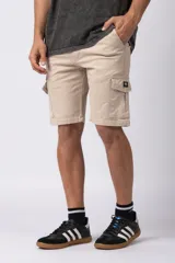 Bermuda cargo de gabardina color beige, con bolsillos laterales amplios con solapa y cierre de broche metálico, cintura con pasadores y etiqueta tejida decorativa.