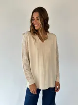 Buzo de tejido de punto ligero, color dorado con brillo sutil, escote en V y manga larga con diseño calado en los puños.