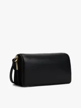 Cartera tipo bandolera de color negro, con acabado liso y solapa frontal. Presenta herrajes metálicos dorados, incluyendo un cierre con el monograma TH y un logo de Tommy Hilfiger en bajo relieve.