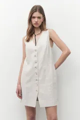 Vestido corto color beige melange, de corte sastrero y confeccionado en lino. Presenta escote en V, cierre frontal con botones y un bolsillo de parche en el pecho.