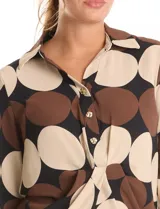 Conjunto de dos piezas compuesto por camisa de manga larga con nudo frontal y pantalón estilo palazzo de pierna ancha. Ambas prendas presentan un estampado geométrico de círculos grandes en tonos marrón, negro y beige. La camisa cuenta con cuello solapa y cierre frontal con botones, mientras que el pantalón posee tiro alto y corte holgado.