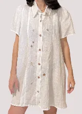 Vestido camisero blanco de lino con cuello clásico, cartera a la vista, mangas cortas acampanadas y bordados de motivos marinos.