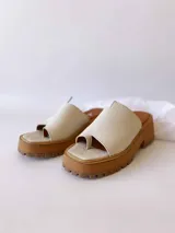 Sandalias de cuero crudo con tira ancha sobre los dedos y suela track color caramelo.
