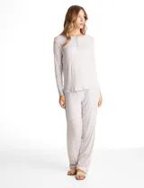 Conjunto de pijama compuesto por una remera de manga larga con escote redondo y cierre frontal de botones, y un pantalón con cintura elástica y lazo de ajuste. Presenta un estampado floral en tonos azules sobre fondo blanco.