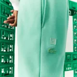 Pantalón de jogging verde agua con cintura elástica y puños ajustados. Presenta un logo de Lacoste y Minecraft en el muslo.