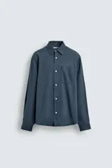 Camisa de corte relajado confeccionada en una mezcla de lyocell y algodón con efecto lavado. Presenta cuello solapa, manga larga con puños abotonados, bolsillo de plastrón en el pecho y cierre frontal con botones.
