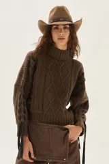 Polera de tejido de punto con diseño de ochos y detalles de tientos en contratono en las mangas. Presenta cuello alto y corte cropped.