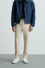 Pantalón chino de corte slim fit, confeccionado en tejido elástico. Presenta bolsillos frontales, bolsillos traseros de vivo con botón y cierre frontal con cremallera y botón.