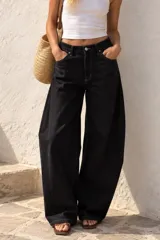 Jean de denim negro tiro alto con diseño de corte barrel leg y costuras en contraste.
