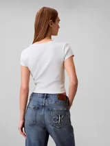 Remera Calvin Klein de manga corta y corte crop top, confeccionada en tejido de punto acanalado de algodón con elastano. Presenta cuello redondo y una pequeña etiqueta rectangular con el logo de la marca en el dobladillo inferior.