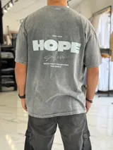 Remera oversize gris con efecto gastado, mangas cortas y estampa con texto blanco en el frente y en la espalda.