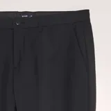Pantalón de vestir de corte slim, color negro, con cierre de botón y cremallera, bolsillos laterales y trabillas para cinturón.