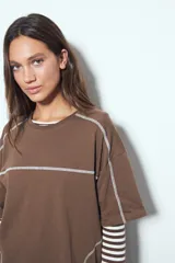 Remera de manga corta con silueta relajada y costuras a la vista en color blanco que contrastan sobre el tejido negro. Presenta un diseño moderno con terminaciones destacadas.