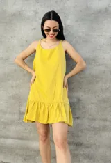 Vestido corto amarillo con breteles finos y falda con volados.