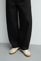 Zapatilla deportiva de estilo retro con diseño de paneles combinados en tonos beige y crema. Presenta detalles en gamuza y una suela de goma en color caramelo.