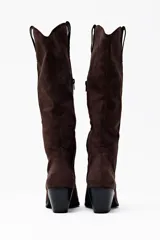 Bota de caña alta color chocolate, confeccionada en suede, con punta en pico y tacón bajo.