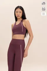 Top deportivo color borgoña con detalles de piping blanco en los bordes. El tejido Sense Pro® tiene tacto suave, transpirabilidad extrema y un soporte medio que realza las formas sin perder libertad.