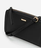 Cartera bandolera pequeña de poliuretano negro, con correa larga y cierre de cremallera.