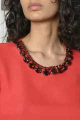 Blusa corta negra de poliéster con mangas largas de gasa abullonadas y cuello redondo. Incluye collar de strass.