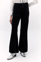 Pantalón de terciopelo negro, de tiro alto y corte acampanado.