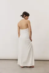 Vestido largo negro de corte al cuerpo con cuello halter y detalle de hebilla metálica dorada en el hombro con tira drapeada.