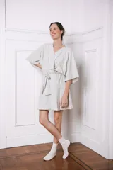 Bata corta de algodón color crema, con escote en V, mangas anchas y cinturón para ajustar en la cintura.