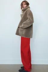 Abrigo reversible de corte recto con cuello solapa, manga larga y cierre frontal de doble botonadura. Presenta un diseño de efecto pelo en un lado y efecto piel en el reverso, con bolsillos de plastrón en el frente.
