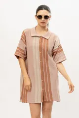 Camisola tipo vestido tejido en algodón con lurex a rayas verticales en tonos marrones, con cuello camisero, mangas cortas y cierre frontal con botones.