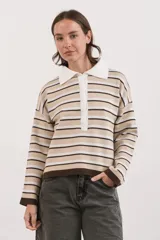 Sweater tipo chomba de tejido bremer, con diseño de rayas horizontales en tonos beige, blanco y marrón chocolate. Presenta cuello polo con cierre frontal de botones y mangas largas.