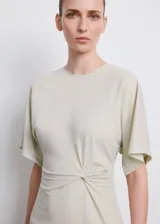 Vestido midi color beige claro, de corte recto, con cuello redondo, mangas cortas holgadas y detalle fruncido en el lateral de la cintura.