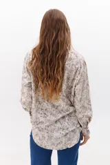 Camisa de corte holgado con estampado floral en tonos marrones y blancos, cuello clásico y cierre frontal con botones.