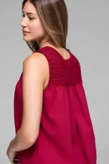 Musculosa color fucsia, con canesú de tejido de punto calado en la espalda y el frente superior, y cuerpo de tela liviana y fluida con pliegues.