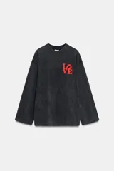 Camiseta de manga larga, corte regular, color negro con efecto lavado o acid wash. Presenta un estampado frontal en rojo con la palabra "LOVE" estilizada.