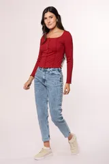 Jean de corte mom con tiro alto, confeccionado en denim de lavado claro con efecto desgastado. Presenta un diseño clásico de cinco bolsillos, cierre con cremallera y botón metálico.