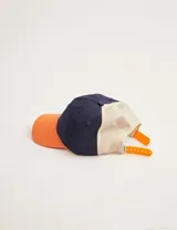Gorra de béisbol azul marino con visera naranja, red beige en la parte trasera y parche bordado en el frente.