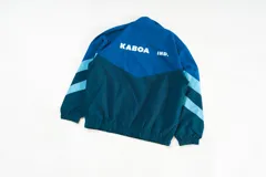Campera deportiva azul confeccionada en nylon liviano, con paneles diagonales en contraste y micrográfico Kaboa aplicados al frente y un gráfico en la espalda.