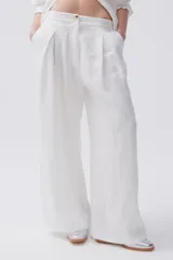 Pantalón de lino blanco, de pierna ancha, con pinzas en el frente, botón en la cintura y bolsillos laterales y traseros.