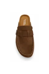 Zueco estilo mocasín negro con acabado efecto gamuza, detalle de hebilla metálica lateral y costuras visibles en el contorno. Cuenta con plantilla anatómica y suela baja.
