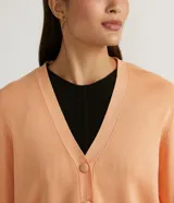 Chaqueta corta de punto color negro, con escote en V, manga larga abullonada, sisa desplazada, abotonado frontal total con botones forrados y puños acanalados.