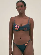 Bikini azul con estampado abstracto en tonos naranja y rosa. El corpiño tiene corte clásico con breteles finos y la bombacha es de tiro bajo con tiras finas regulables.